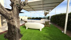 a white couch sitting on top of green grass at Casa Del Mar, piscina privada frente al mar in Cullera