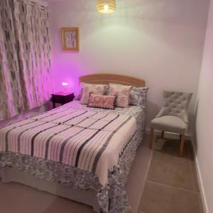 a small bedroom with a bed and a chair at A beautiful stylish home in city centre in Camberley
