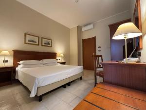 ein Schlafzimmer mit einem Bett, einem Schreibtisch und einer Lampe in der Unterkunft Naples Park Hotel in Marigliano