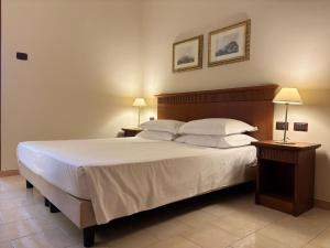 ein Schlafzimmer mit einem großen weißen Bett und zwei Nachttischen in der Unterkunft Naples Park Hotel in Marigliano + 2 Fotos