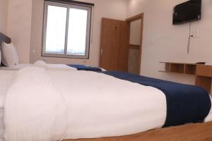 a bedroom with a large white bed with a window at Hotel Lakhdatar in Kota