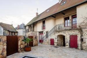an old house with red doors and a courtyard at Sur Les Roches in Dracy-lès-Couches