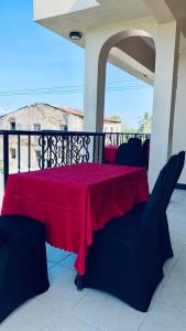 a red table and chairs on a porch with a view at Agape hostel in Bagamoyo +8 photos