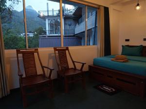 a bedroom with two chairs and a bed and a window at Isha Unity Cottage in Nallathanniya