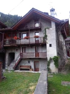 a house with a balcony and a bench in front of it at Maison Leveque in Brusson
