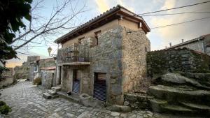an old stone building with a balcony on a street at A Bolota, Casa rural in Trevejo