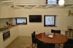 a kitchen with a table and a tv on the wall at A Bolota, Casa rural in Trevejo