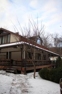 a house with a wooden deck in the snow at Penates Aparthotel in Koropovo