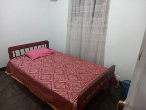 a bedroom with a bed with a pink pillow at Volunteer lanka in Padukka
