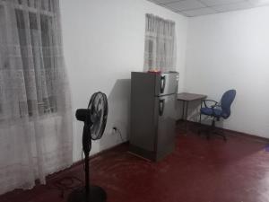 a room with a fan and a desk and chairs at Volunteer lanka in Padukka