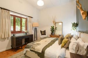 a bedroom with a bed and a desk and a mirror at Am Flus- at the river in Stellenbosch