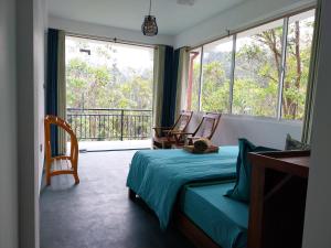 a bedroom with a bed and a balcony with chairs at Isha Unity Cottage in Nallathanniya