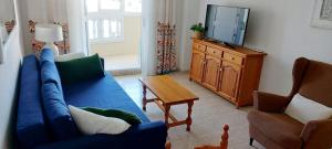 a living room with a blue couch and a tv at SOLMAR La Mata Beach in Torrevieja
