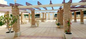 an outdoor patio with a pergola and chairs and plants at SOLMAR La Mata Beach in Torrevieja