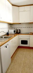 a kitchen with white cabinets and a sink at SOLMAR La Mata Beach in Torrevieja