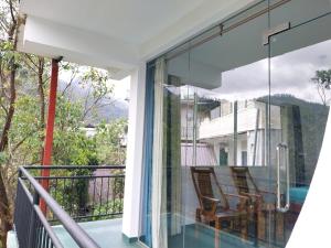 a balcony with glass doors and chairs on it at Isha Unity Cottage in Nallathanniya