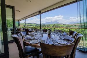 ein Esszimmer mit einem Tisch und Stühlen sowie einem großen Fenster in der Unterkunft Clos Malverne Wine Estate in Stellenbosch