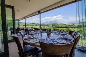 a dining room with a table and chairs and a large window at Clos Malverne Wine Estate in Stellenbosch