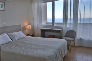 a bedroom with a bed and a desk and a window at Hôtel restaurant Le Belvedere De Coti in Coti-Chiavari