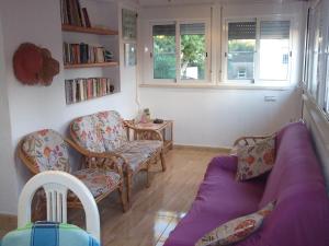 uma sala de estar com um sofá roxo e cadeiras em Apartamento Gerard em Riumar