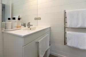 a white bathroom with a sink and towels at Hideaway Cottage, Tauranga, so close to Bethlehem & Mount Maunganui in Tauranga +13 photos