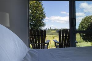a bedroom with a bed and two chairs looking out the window at Hideaway Cottage, Tauranga, so close to Bethlehem & Mount Maunganui in Tauranga