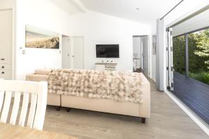 a living room with a couch and a tv at Hideaway Cottage, Tauranga, so close to Bethlehem & Mount Maunganui in Tauranga