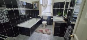 a bathroom with a tub and a toilet and a sink at 14th on West in Graaff-Reinet +35 photos