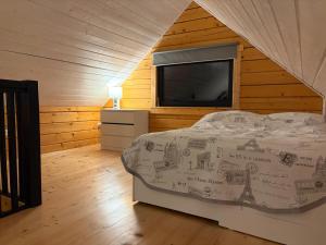 a bedroom with a bed and a flat screen tv at Na Wrzosowej, domy z bala PREMIUM, blisko Suntago in Franciszków