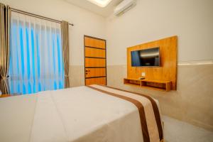 a bedroom with a bed and a flat screen tv at Wana Kubu Suite and Dormitory in Ngurah Rai International Airport