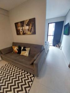 a living room with a brown couch and a rug at Prime Flat Palladium Mar & Piscina in São Vicente