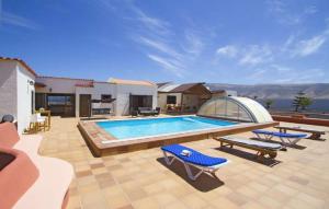 een zwembad met twee blauwe stoelen en een huis bij Villa Vista Graciosa in Las Laderas