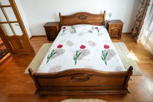 a bedroom with a wooden bed with red flowers on it at Casa de vacanță in Călimăneşti