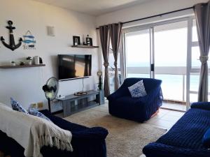 a living room with a tv and a couch and a chair at Stella Maris 135 in Amanzimtoti