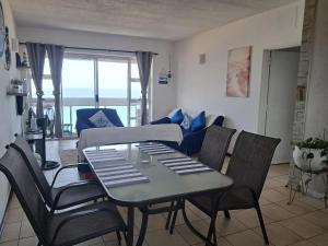 a dining table and chairs in a living room at Stella Maris 135 in Amanzimtoti