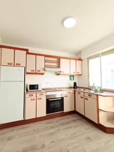 a kitchen with wooden cabinets and a white refrigerator at Apartamento Maruja Mallo in Viveiro