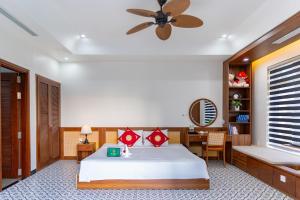 a bedroom with a bed and a desk and a ceiling fan at B'Villa Luxury in Dong Hoi