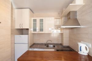 a kitchen with white cabinets and a sink and a refrigerator at Apartamentos Ripoll Ibiza in Ibiza Town