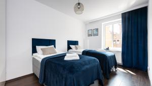 a bedroom with two beds with blue sheets and a window at Flatbook Comfort Old Town 8 in Gdańsk