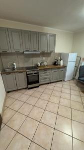 a kitchen with white cabinets and a tiled floor at Apartament 10 Słoneczna in Ełk