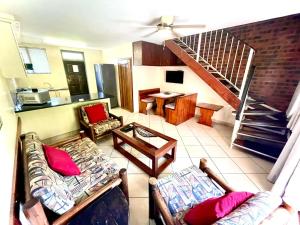 a living room with two couches and a staircase at Flamingo Holiday Flats in St Lucia