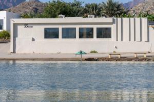 a house with an umbrella next to a body of water at SS Resorts - Private Luxury Villa in Hatta +26 photos
