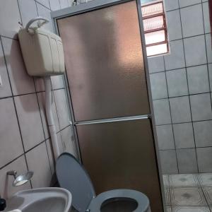 a bathroom with a shower with a toilet and a sink at Suíte in Garopaba
