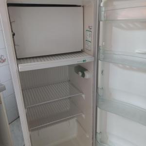 an empty refrigerator with its door open in a kitchen at Suíte in Garopaba