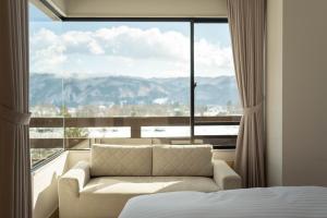 ein Schlafzimmer mit einer Couch vor einem großen Fenster in der Unterkunft Hotel Goryukan in Hakuba
