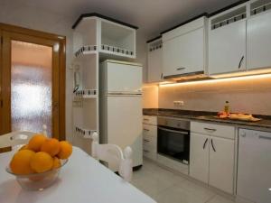 a kitchen with white cabinets and a bowl of oranges on a table at Harmony Seafront 365 by Can Ventet in Port de Pollensa