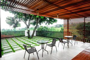 a patio with tables and chairs and a tree at RedDoorz near Bukitsari Semarang in Jatingaleh