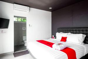 a bedroom with a bed with a red and white blanket at RedDoorz near Bukitsari Semarang in Jatingaleh