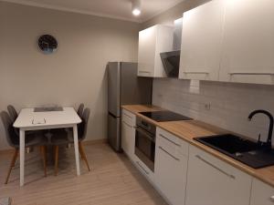 a kitchen with white cabinets and a table and a sink at Apartament 26 in Drawsko Pomorskie