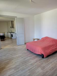 a bedroom with a red bed and a kitchen at Lieu charmant in Gimeux